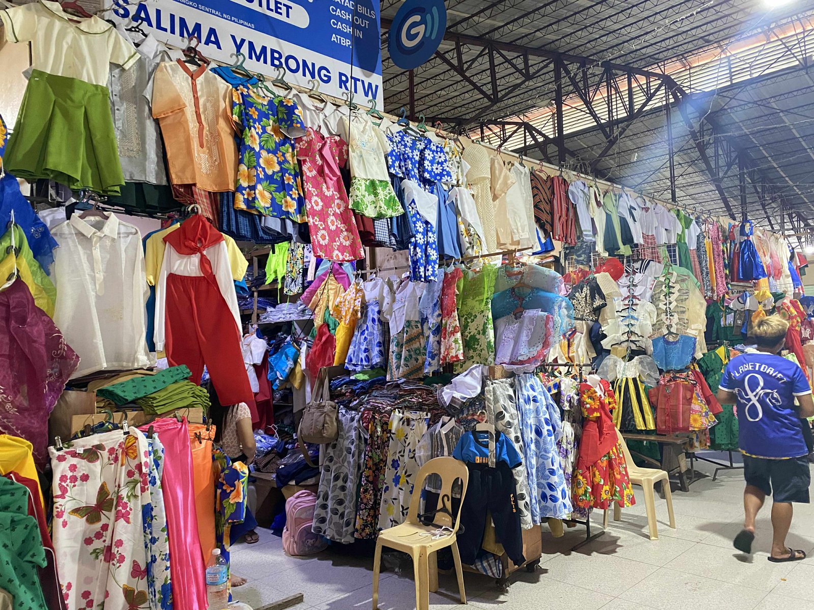Vibrant textile market stalls displaying clothes, fabrics, and blankets sold by vendors
